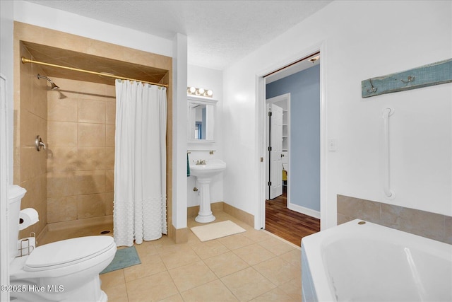 bathroom with a stall shower, a textured ceiling, toilet, and tile patterned floors