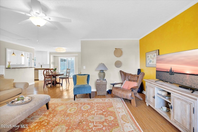 living room featuring light wood-style floors, ceiling fan, ornamental molding, and a textured ceiling