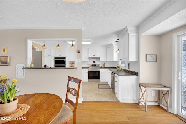 kitchen featuring stainless steel appliances, dark countertops, white cabinetry, a sink, and under cabinet range hood