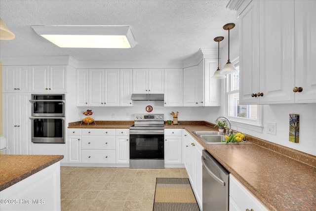 kitchen with under cabinet range hood, a sink, white cabinetry, appliances with stainless steel finishes, and dark countertops