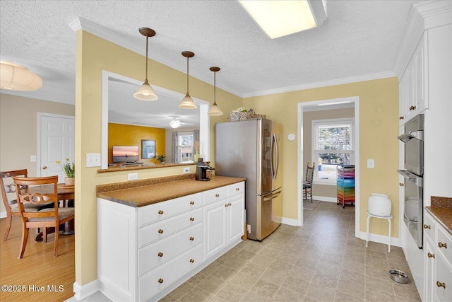 kitchen featuring white cabinetry, appliances with stainless steel finishes, crown molding, and decorative light fixtures