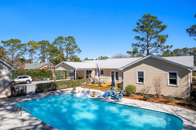 pool with french doors, fence, and a wooden deck