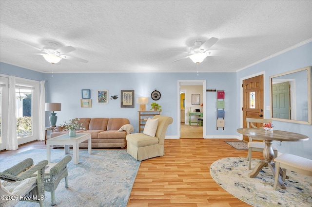 living area featuring ornamental molding, light wood-type flooring, ceiling fan, and a textured ceiling