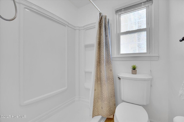 bathroom featuring toilet and curtained shower