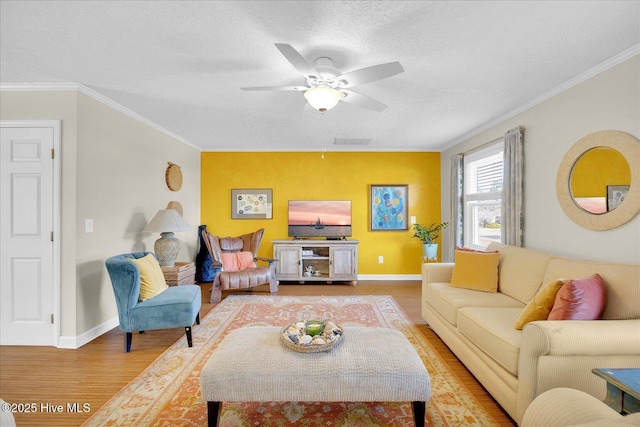 living room with ornamental molding, light wood-type flooring, a textured ceiling, and baseboards