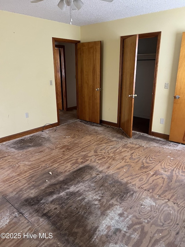 unfurnished bedroom with a closet, a textured ceiling, baseboards, and wood finished floors