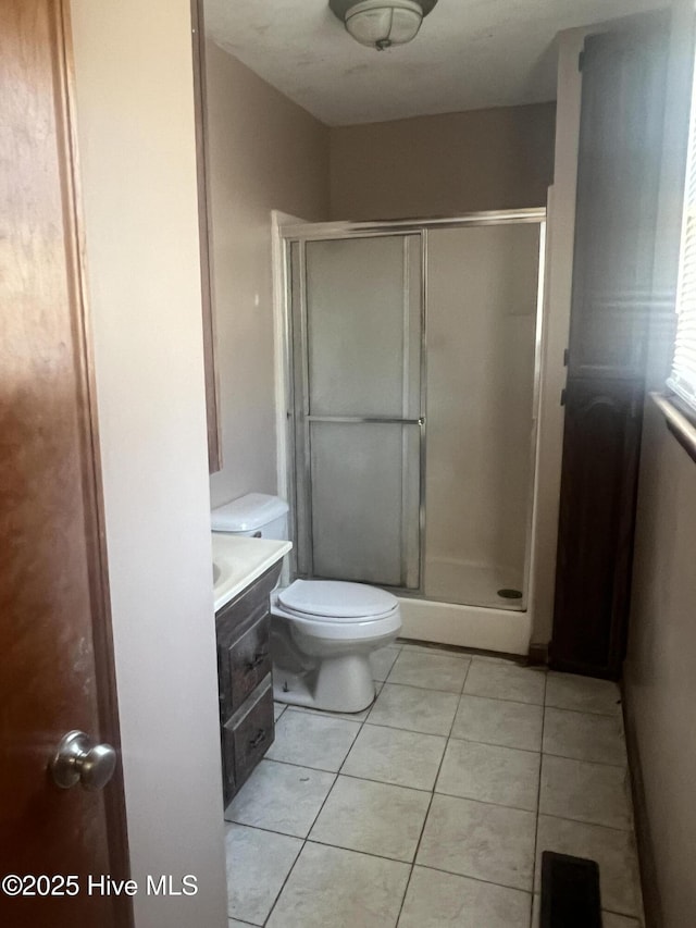 full bathroom featuring a stall shower, tile patterned flooring, vanity, and toilet