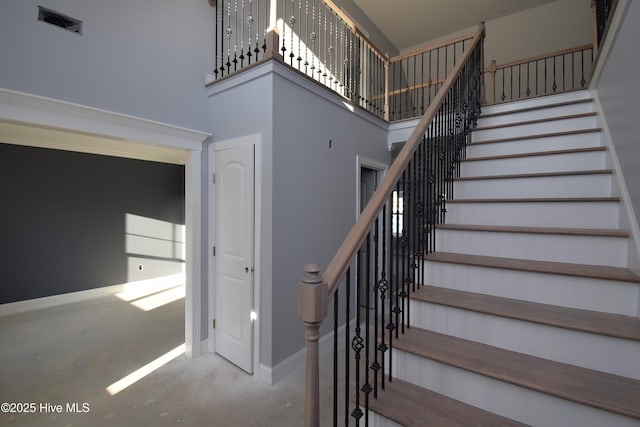 stairway with a towering ceiling and concrete flooring