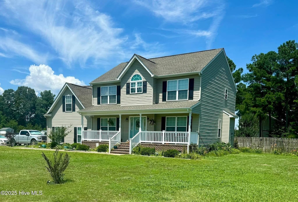 view of front of home featuring covered porch, roof with shingles, fence, and a front lawn