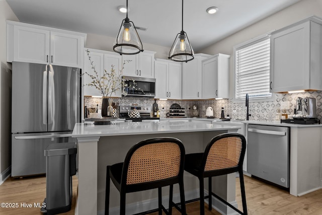 kitchen featuring white cabinetry, a kitchen island, appliances with stainless steel finishes, decorative backsplash, and pendant lighting