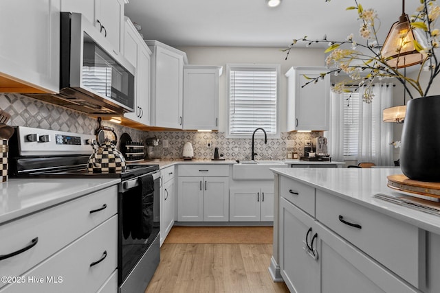 kitchen featuring appliances with stainless steel finishes, tasteful backsplash, hanging light fixtures, sink, and white cabinetry