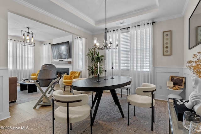 dining area featuring hardwood / wood-style flooring, crown molding, a chandelier, and a raised ceiling