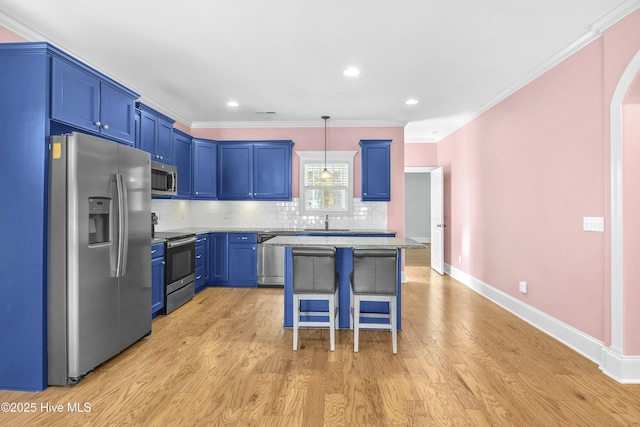 kitchen featuring tasteful backsplash, a breakfast bar area, stainless steel appliances, decorative light fixtures, and light wood-type flooring