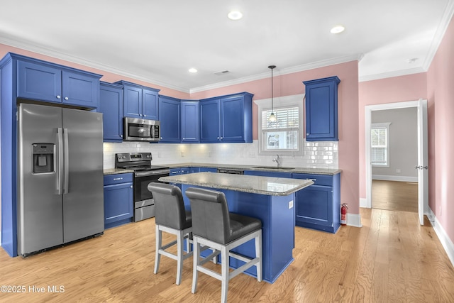 kitchen featuring appliances with stainless steel finishes, hanging light fixtures, a breakfast bar area, and light hardwood / wood-style flooring