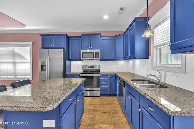 kitchen featuring a kitchen bar, appliances with stainless steel finishes, sink, pendant lighting, and a kitchen island