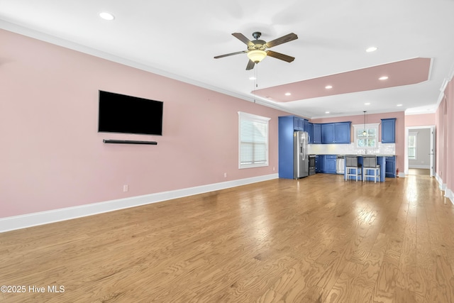 unfurnished living room featuring crown molding, ceiling fan, and light hardwood / wood-style flooring