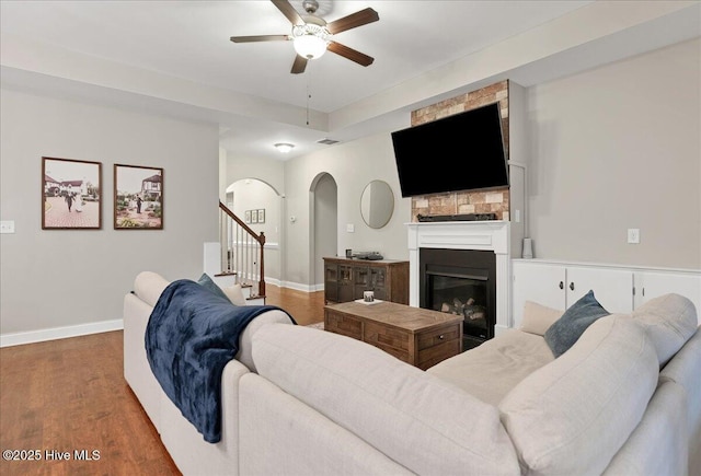 living room featuring visible vents, a fireplace, baseboards, and wood finished floors