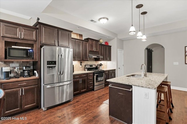 kitchen with dark wood-style floors, decorative backsplash, appliances with stainless steel finishes, a sink, and under cabinet range hood