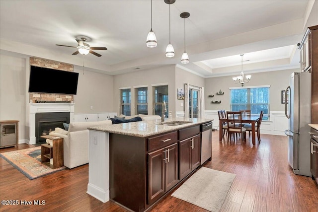 kitchen with dark wood finished floors, stainless steel appliances, a raised ceiling, a sink, and dark brown cabinetry