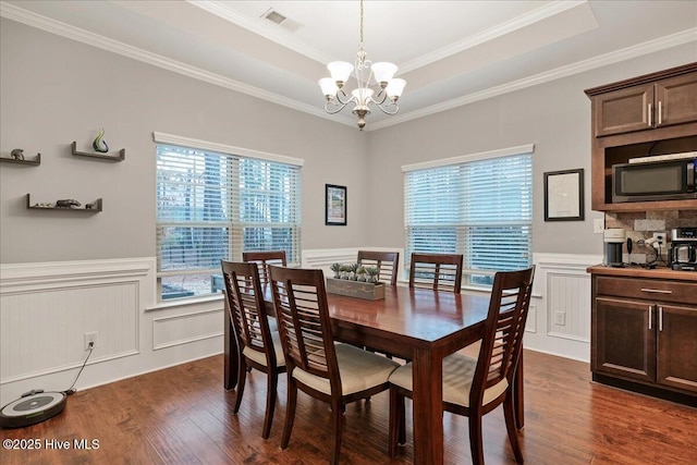 dining room featuring visible vents, wainscoting, dark wood-style flooring, a tray ceiling, and a chandelier