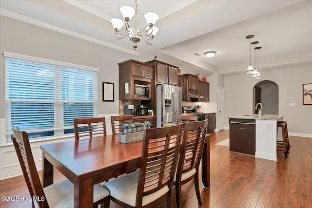 dining room with arched walkways, dark wood-style floors, an inviting chandelier, a tray ceiling, and crown molding