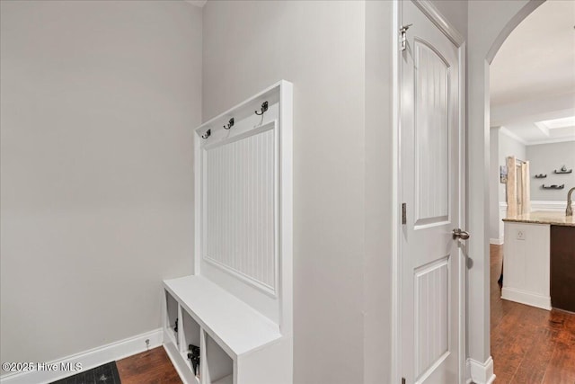 mudroom with dark wood-style floors, arched walkways, and baseboards