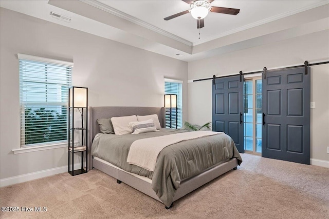 bedroom with light carpet, a barn door, a tray ceiling, and baseboards