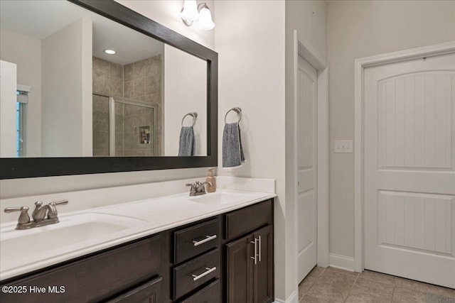 bathroom featuring tile patterned flooring, a sink, a shower stall, and double vanity