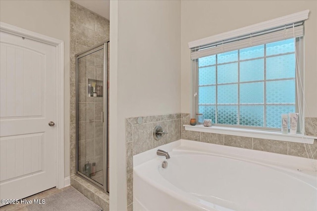 bathroom featuring a shower stall and a bath