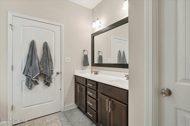 full bathroom featuring tile patterned flooring, a sink, baseboards, and double vanity