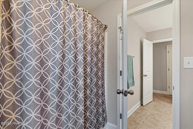 full bath with curtained shower and baseboards