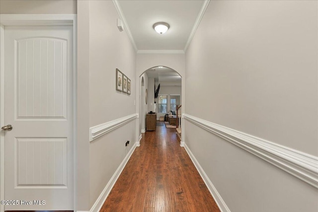 hall with arched walkways, ornamental molding, dark wood-style floors, and baseboards