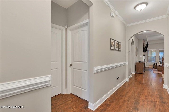 corridor featuring baseboards, arched walkways, dark wood finished floors, and ornamental molding