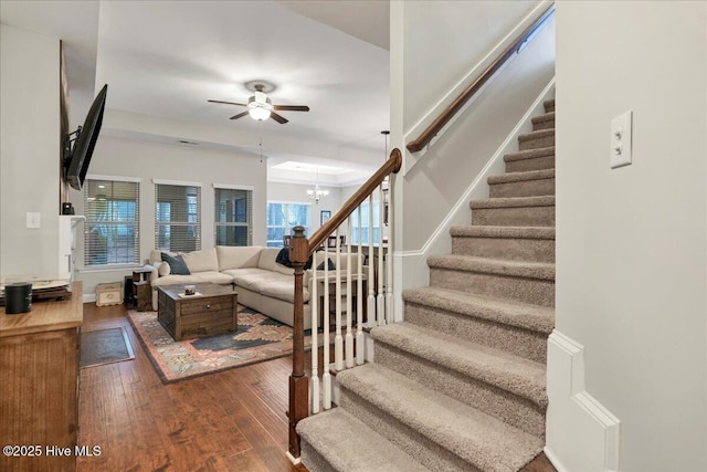 stairway with wood-type flooring and ceiling fan with notable chandelier