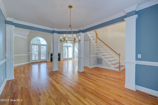 unfurnished dining area featuring decorative columns, visible vents, light wood-style flooring, baseboards, and stairs