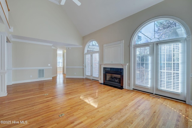 unfurnished living room featuring high vaulted ceiling, a tile fireplace, visible vents, and light wood-style flooring