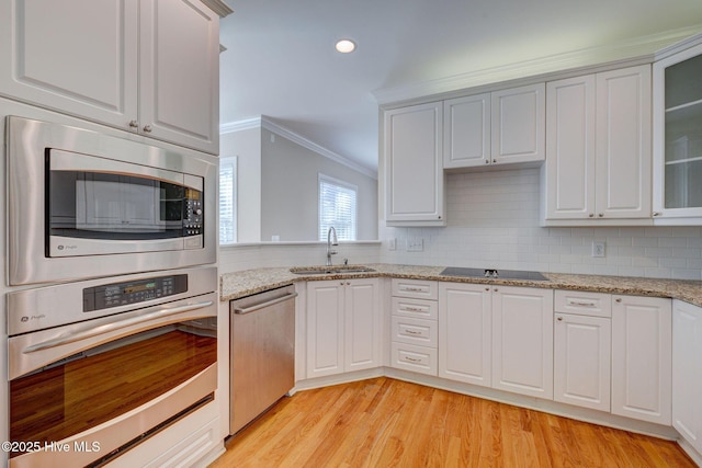 kitchen with crown molding, decorative backsplash, stainless steel appliances, and a sink