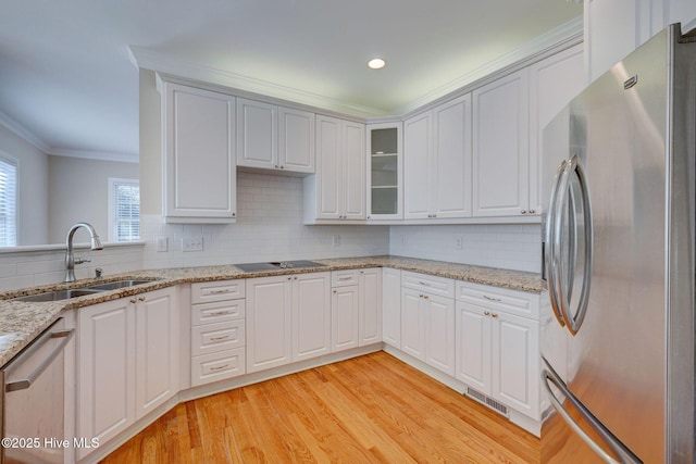 kitchen with a sink, appliances with stainless steel finishes, light wood-type flooring, tasteful backsplash, and crown molding