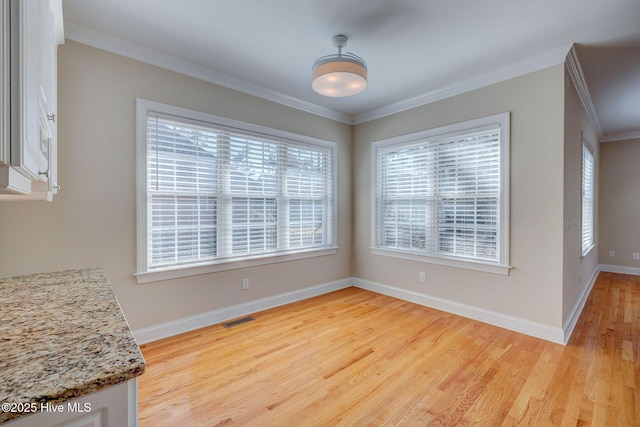 dining room with ornamental molding, baseboards, visible vents, and light wood finished floors