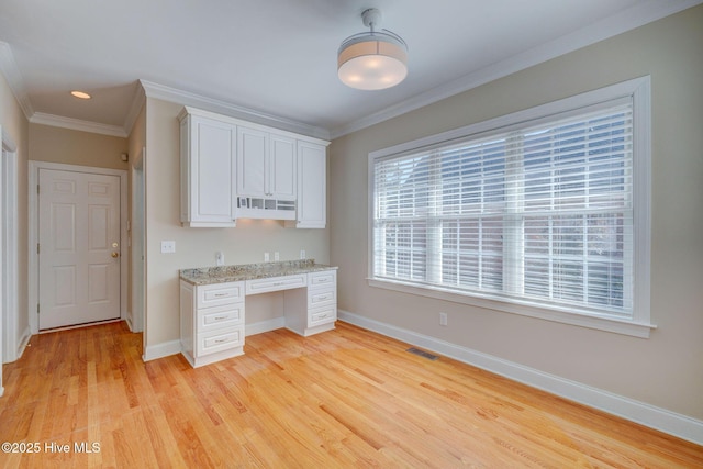 kitchen featuring light wood-style flooring, visible vents, baseboards, built in study area, and crown molding