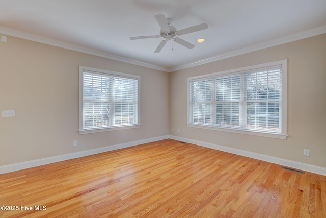 empty room featuring plenty of natural light, visible vents, ornamental molding, and wood finished floors