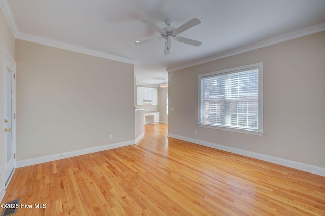 spare room featuring light wood-style floors, ceiling fan, baseboards, and crown molding