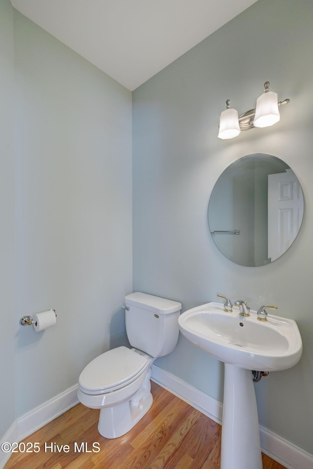 bathroom featuring a sink, wood finished floors, toilet, and baseboards