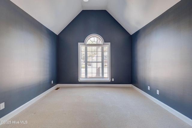 carpeted spare room with visible vents, vaulted ceiling, and baseboards