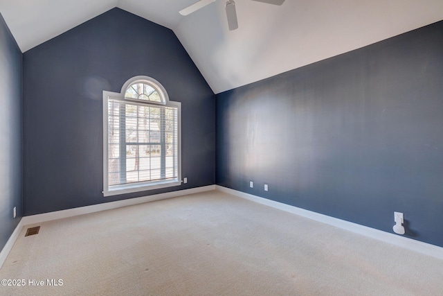 carpeted spare room with lofted ceiling, baseboards, visible vents, and a ceiling fan