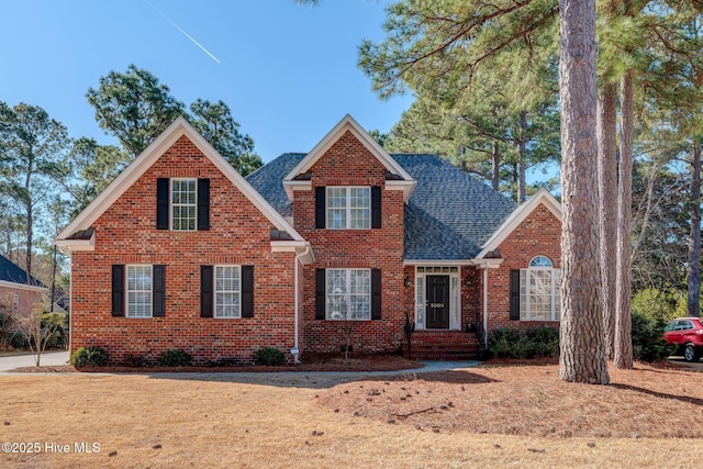 traditional-style home with a shingled roof and brick siding