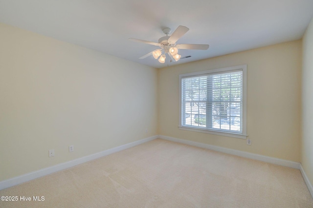 spare room featuring baseboards, visible vents, a ceiling fan, and light colored carpet