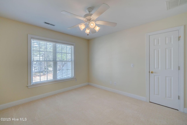 empty room featuring ceiling fan, carpet floors, visible vents, and baseboards