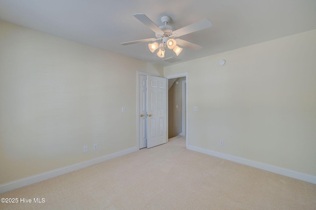 spare room with baseboards, a ceiling fan, and light colored carpet