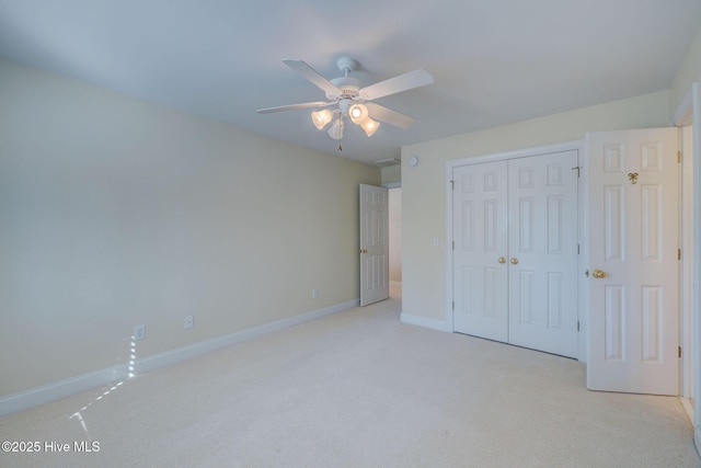 unfurnished bedroom with a ceiling fan, baseboards, a closet, and light colored carpet